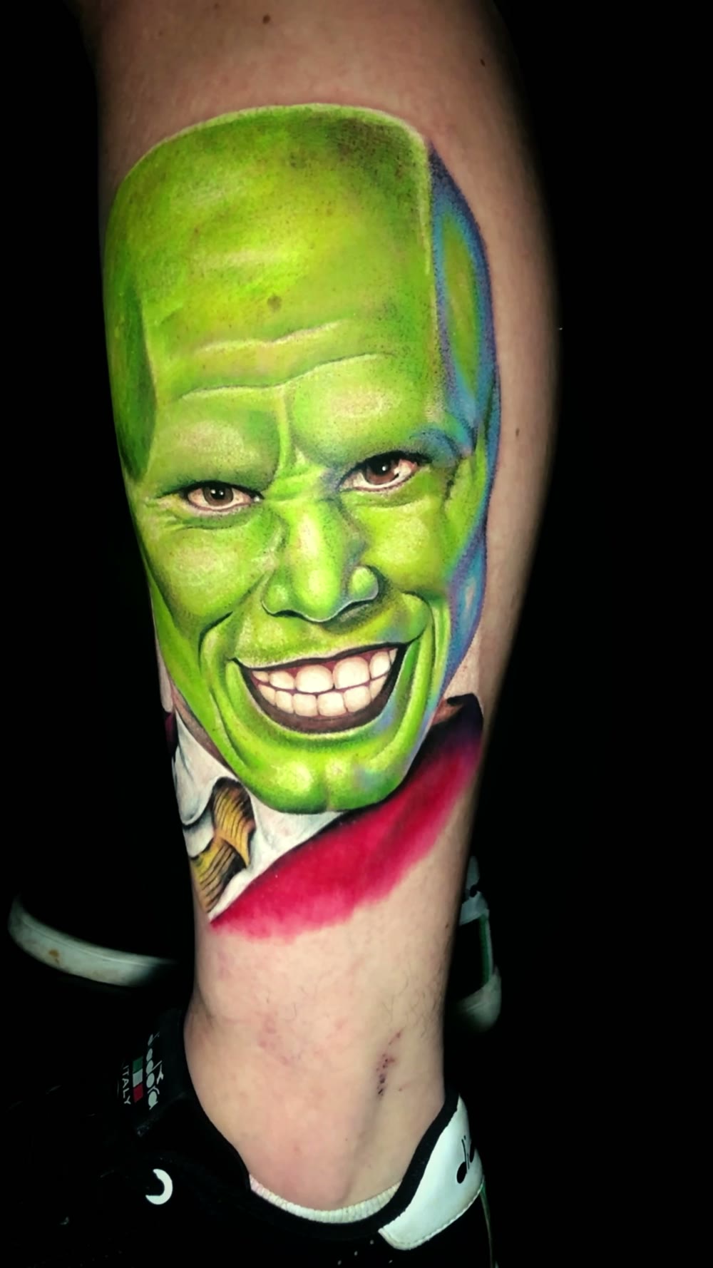 Tatuagem realista colorida, personagem de máscara verde na panturrilha